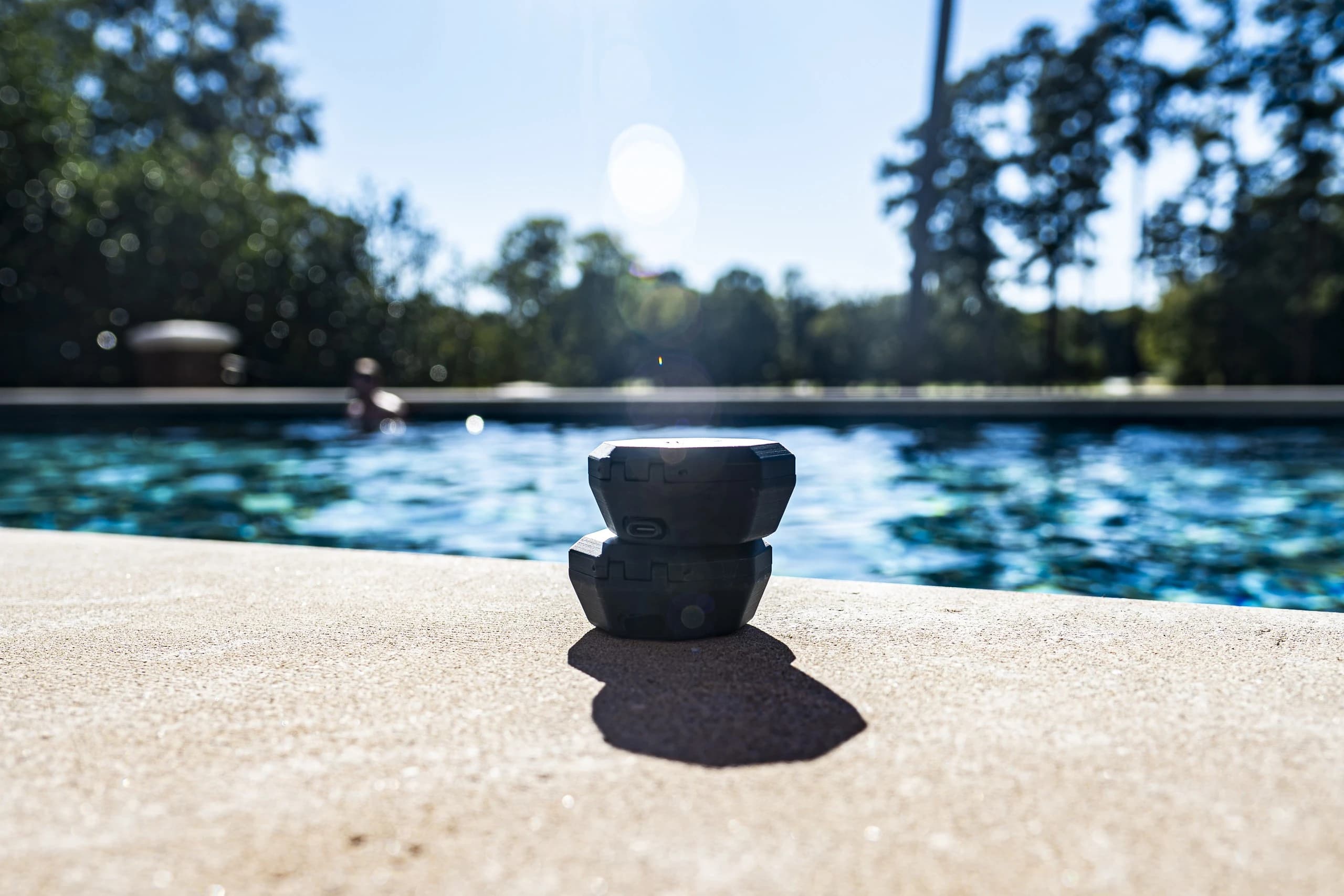 The case and buds stacked on the pool's edge